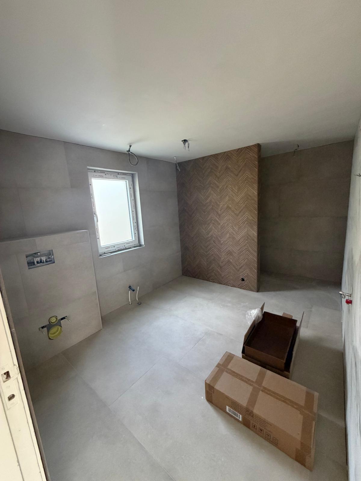 Moderne badkamer met betonlook tegels en houten visgraat accentwand — badkamerrenovatie Noord-Holland