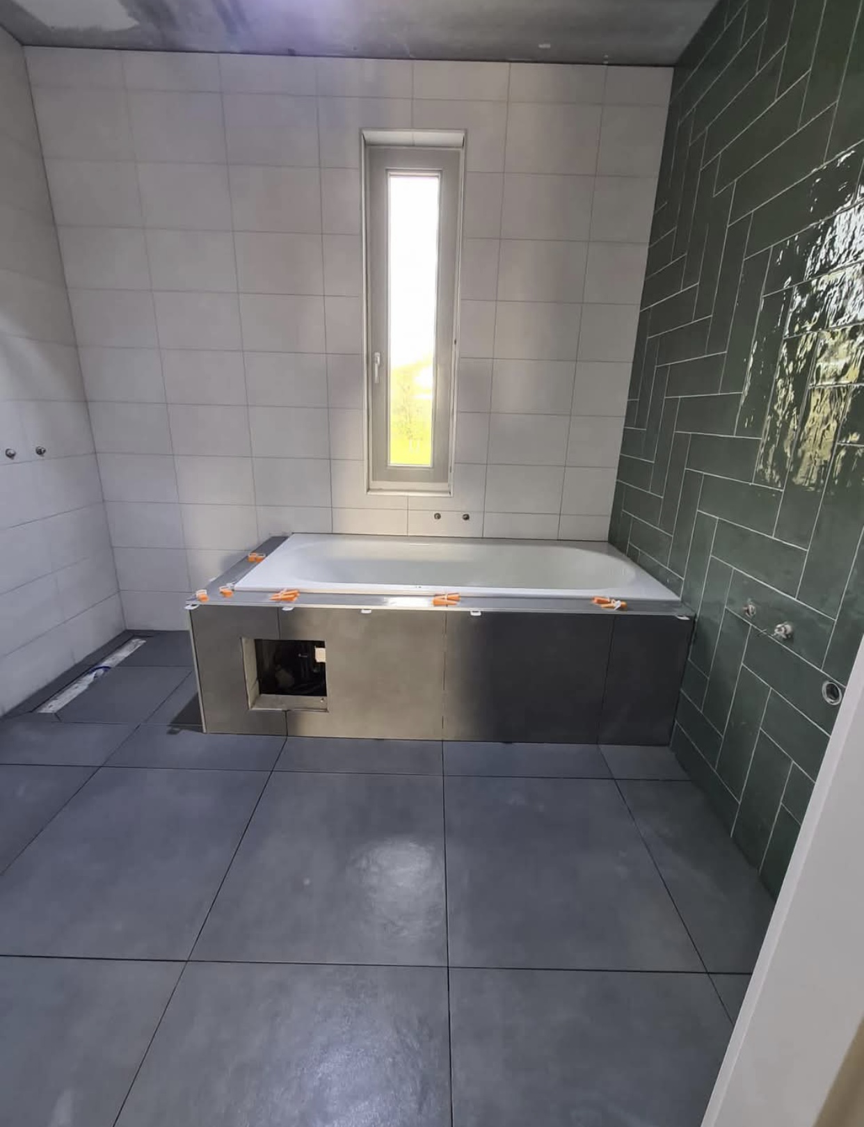 Badkamer met donkergroene visgraat tegelwand, witte wandtegels en antracietgrijze vloertegels — tegelzetter Noord-Holland