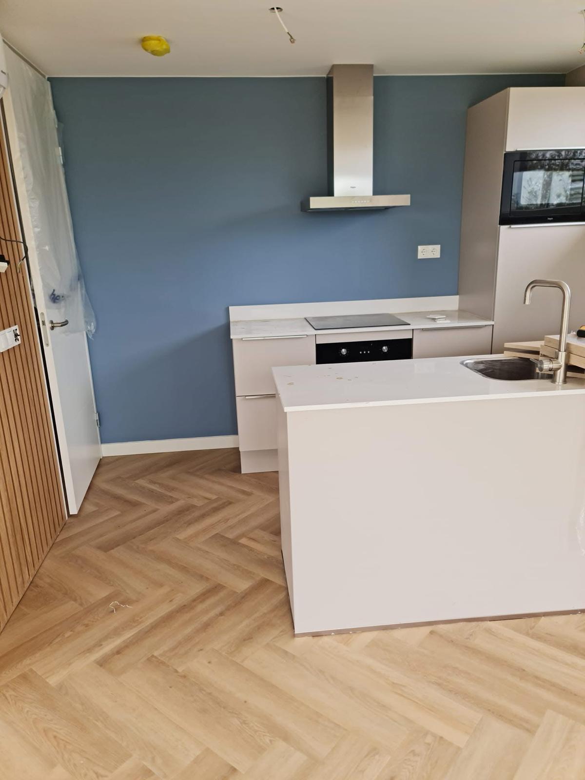 Keuken met blauwe accentmuur en visgraatvloer
