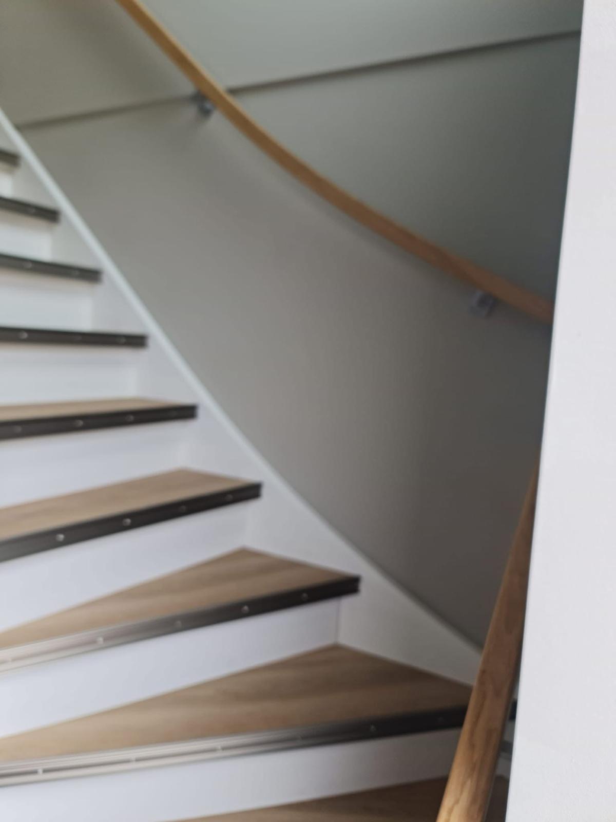 Trappenhuis met glad stucwerk en houten trap