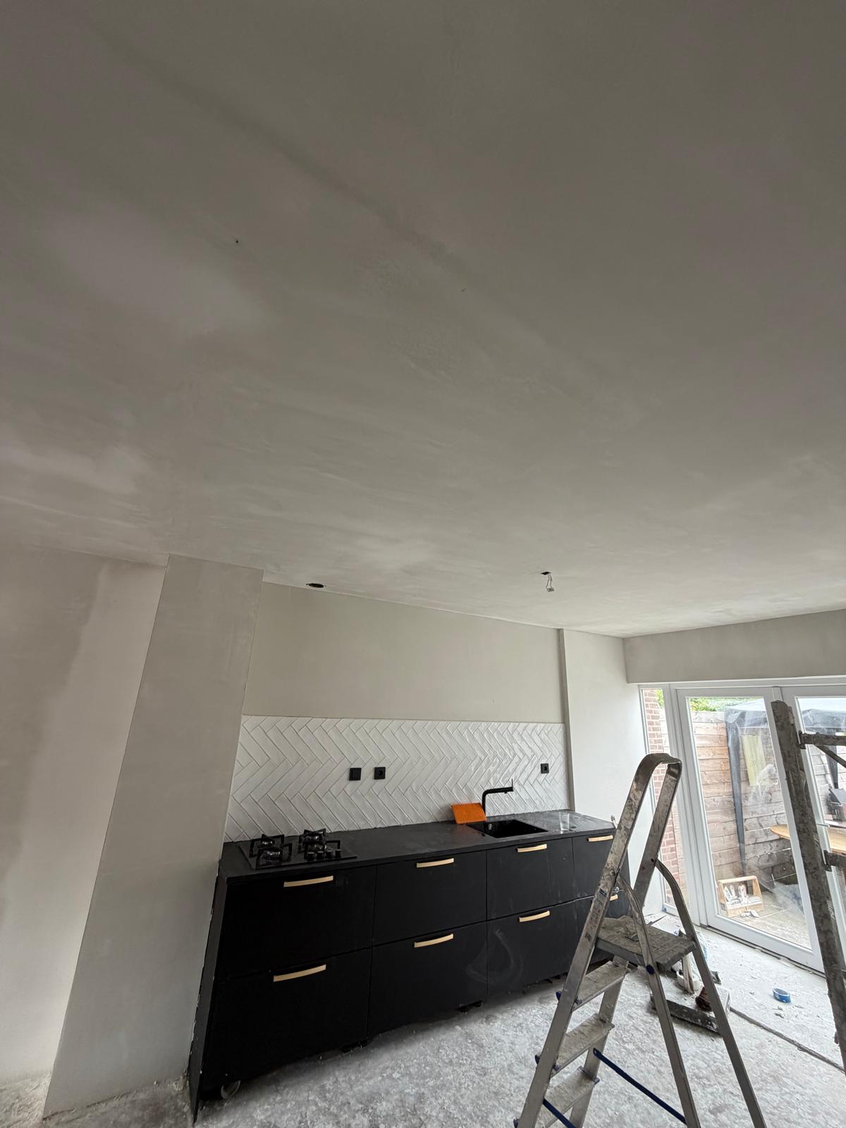 Open keuken met sausklaar gestuukt plafond en visgraat tegelwand — stucadoor Noord-Holland